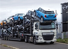 front view of an Acumen Logistics car transporter transporting a variety of colours mini's