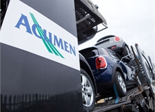 close up low angle shot of Acumen Logistics logo on a car transporter with mini's visible loaded on the car transporter in the background