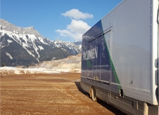 view down the side of an Acumen Logistics enclosed car transport lorry at the base of a picturesque mountain.