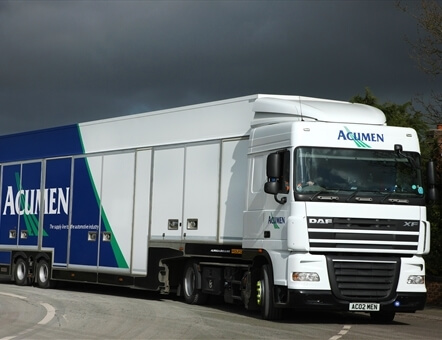 Acumen Logistics covered car transport lorry driving round a corner with overcast sky