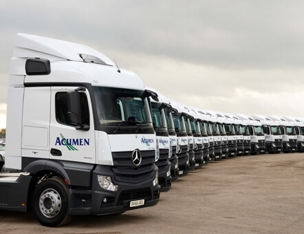 side view of a large number of new Acumen Logistics lorries all lined up in a slight curve