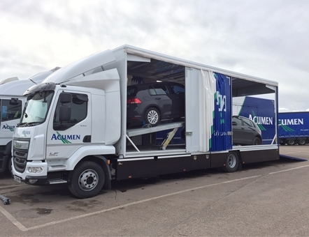 one of acumen enclosed car transporters with it's side open and 2 cars loaded on the lorry for covered car transport.